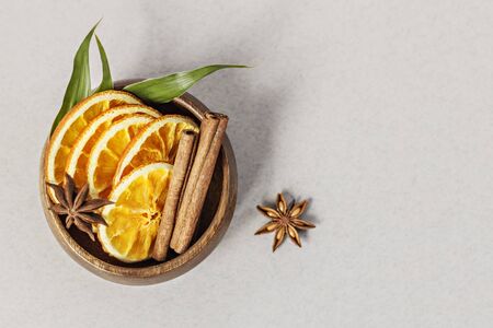 In a wooden bowl, sliced orange, cinnamon sticks and anise stars on a gray background. Aromatherapy.Home spa conceptの写真素材