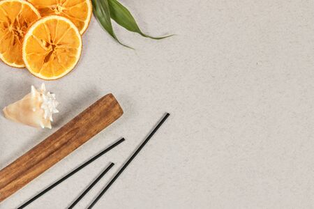 Incense sticks with a stand, sliced orange circles in a wooden bowl on a gray background. Also a seashell.Aromatherapy. The concept of home Spa.の写真素材