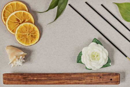 Incense sticks with a stand, sliced orange circles in a wooden bowl on a gray background. Also a candle in the form of a flower and a seashell.Aromatherapy. The concept of home Spa.の写真素材
