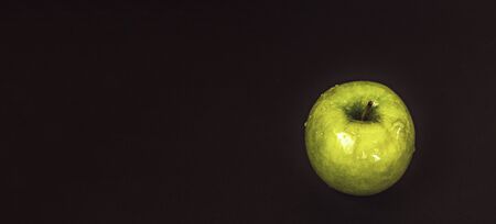 Juicy fresh green apple with water droplets on a black background with space for text. Bannerの写真素材