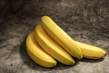 Ripe delicious yellow bananas on a dark background.の写真素材