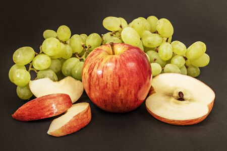 Ripe juicy apples with grapes on a black background.の写真素材