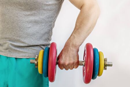 Male athlete lifting a heavy dumbbell with one hand