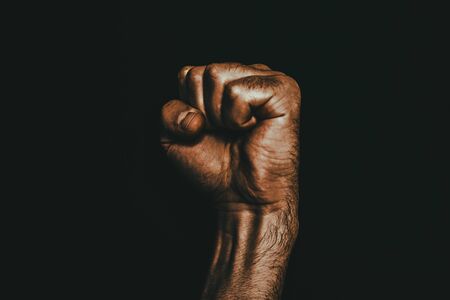 Male black fist on a black background. Aggressiveness, masculinity, the concept of challenge.の写真素材