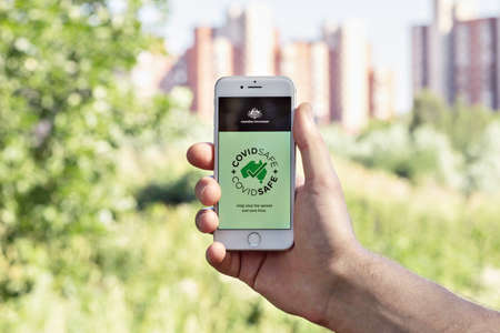 A man's Hand holds a phone with the CovidSafe appのeditorial素材