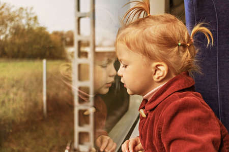 Little girl looking out the train window at sunset.の写真素材