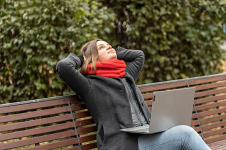 Young smiling woman videochat by smartphone sitting on a park bench. Video call to a mobile phone....
