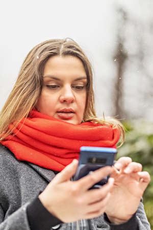 Young woman holds a smartphone and checks messages, of the street in the park