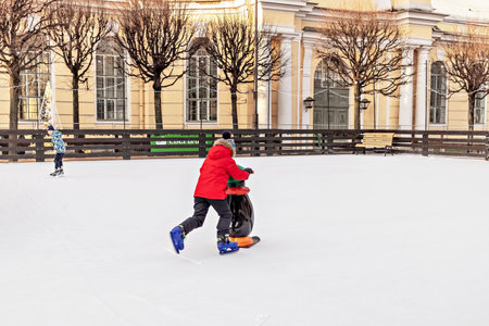 Children skate on the ice rink in the city square. Christmas holidays.