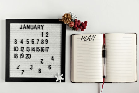 Notepad for taking notes of goals and plans for the new year, calendar and Christmas tree decoration on the desktop. Inscription in English Plane.の写真素材
