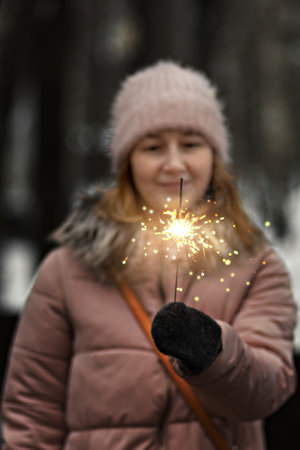 Christmas lights are bright splashes burning in the hands of a blurry happy woman in the park. Sparkler. Emotions, New Year's mood.Winter holidays.の写真素材
