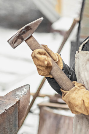 The boy, the blacksmith's son, stands at the anvil. The process of forging.の写真素材