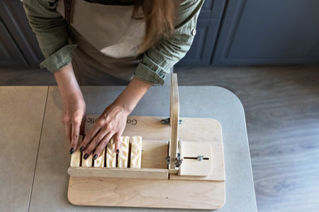 A woman makes handmade natural soap. The finished soap is cut into pieces using special machine. Home spa. Small business.の写真素材