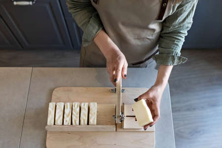 A woman makes handmade natural soap. The finished soap is cut into pieces using special machine. Home spa. Small business.の写真素材