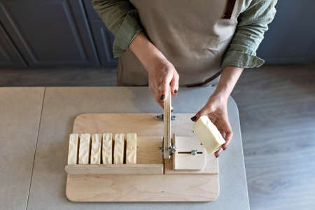 A woman makes handmade natural soap. The finished soap is cut into pieces using special machine. Home spa. Small business.の写真素材