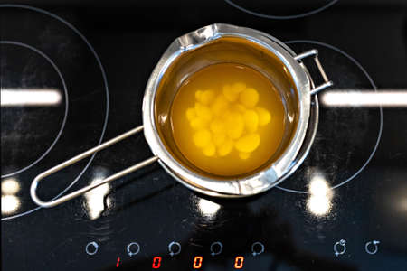Top view of organic cocoa butter melted in a water bath for the preparation of body skin care...