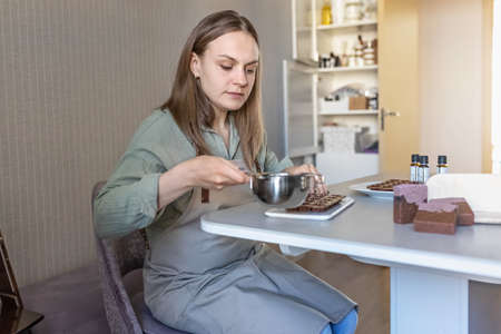 Soap maker a woman pours hot organic cocoa butter with aromatic oils into molds for making cosmetics for body skin careの写真素材