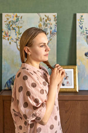Portrait of a young woman straightening her hair in a room at home. Home environment. Interior.の写真素材