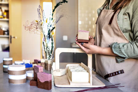 A soap-maker girl holds a piece of freshly brewed handmade soap in her hands.Cooking process.Home spa.Small businessの写真素材