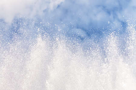 Background of water jets and fountain splashes against a blue sky with clouds.の写真素材