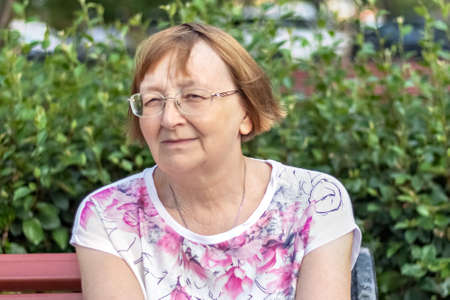 Portrait of a smiling elderly woman on a bench.の写真素材