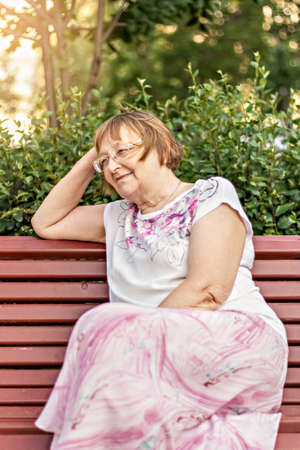 Portrait of a smiling elderly woman on a bench.の写真素材