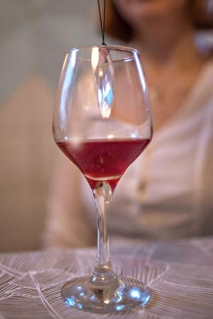 A glass of red wine on the table with a crystal inside.の写真素材