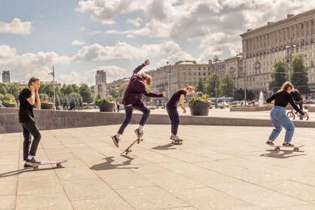 A group of teenagers skateboarding on the square. Performing stunts, extreme sports.のeditorial素材