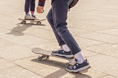 The legs of teenage boys skateboarding on the square. Performing stunts, extreme sports.