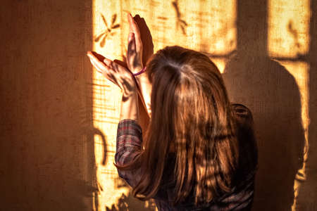 A young woman catches the shadow of a dragonfly on the wall.の写真素材