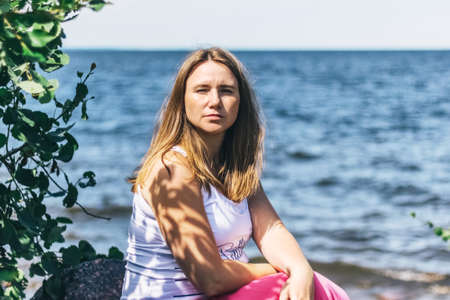 A pregnant woman is sitting on the beach.の写真素材