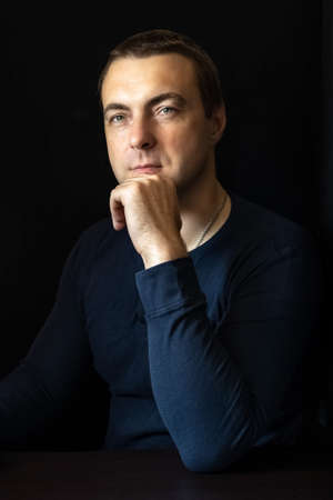 Portrait of a young man in a blue shirt in a dark key.