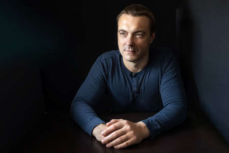 Portrait of a young man in a blue shirt in a dark key.の写真素材