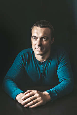 Portrait of a young man in a blue shirt in a dark key.の写真素材