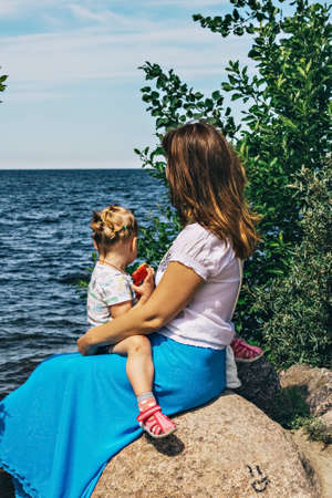 A young woman with a child is sitting on the seashore.の写真素材