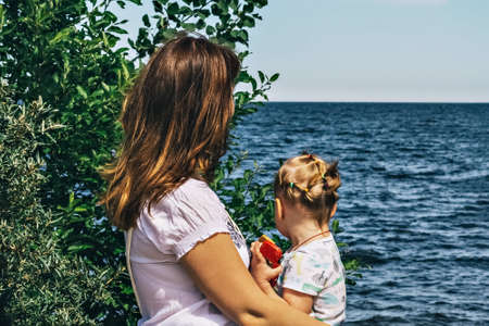 A young woman with a child is sitting on the seashore.の写真素材