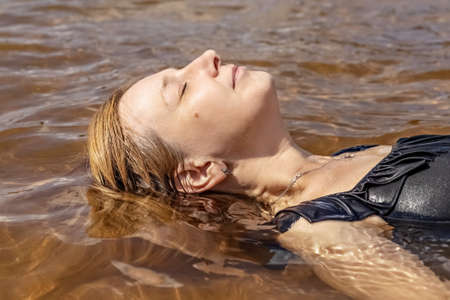 Portrait of a young woman close-up in the water. Swimming in the lake.の写真素材
