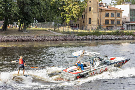 A young woman rides on a water board attached to a boat on the riverのeditorial素材
