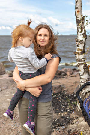 Mom with a little daughter in her arms hugging on the beach.の写真素材