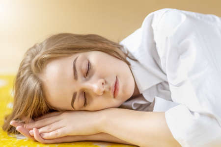 Portrait of a young teenage girl with closed eyes lying on the floor. Stress, depression,...
