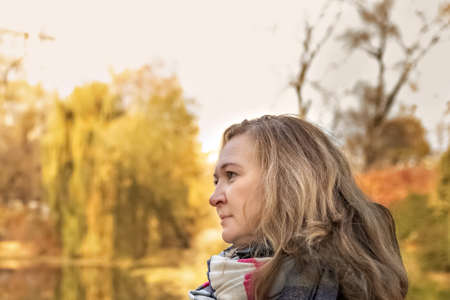 Portrait of a woman on the shore of a pond in an autumn park.の写真素材