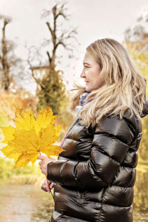 Portrait of a woman on the shore of a pond in an autumn park.の写真素材