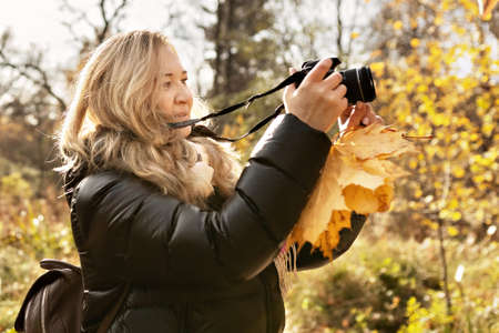 Portrait of a photographer's woman in an autumn park. Photographing nature.の写真素材