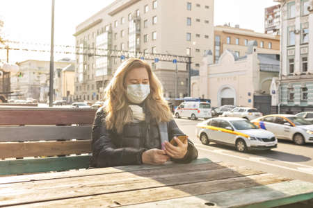 Portrait of a young woman in an outdoor cafe on the street with a phone in her hands.Pandemic coronavirusの写真素材