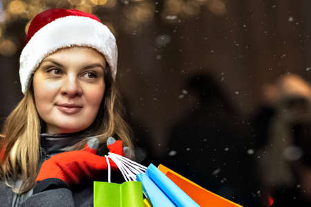 A young woman's Christmas shopping. Colorful bright paper bags with gifts. A walk through the Christmas shops of a young beautiful woman. Garlands, lights.Celebrating the New Year.の写真素材