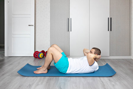 A strong, healthy man with muscles, training at home. Exercises for the muscles of the press.の写真素材
