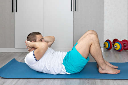 A strong, healthy man with muscles, training at home. Exercises for the muscles of the press.の写真素材