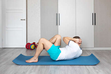 A strong, healthy man with muscles, training at home. Exercises for the muscles of the press.の写真素材
