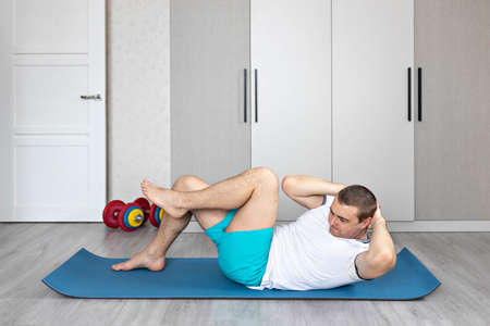 A strong, healthy man with muscles, training at home. Exercises for the muscles of the press.の写真素材