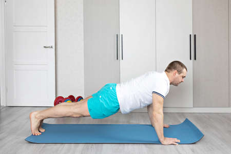 A strong, healthy man with muscles, training at home in the plank position. fitness at homeの写真素材